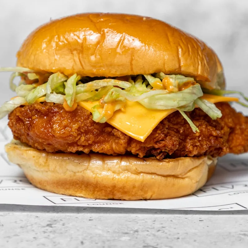 A crisp fried chicken fillet with melted cheese and shredded lettuce in a toasted potato bun